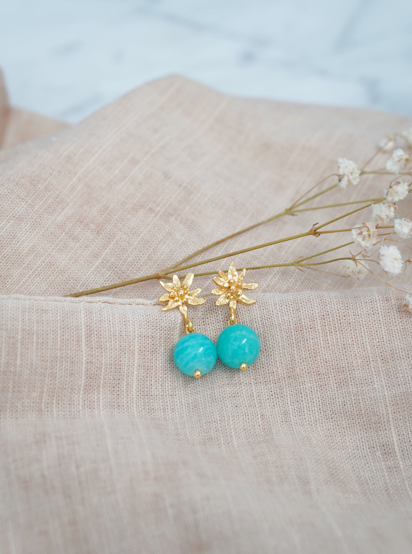 Amazonite flower earrings featuring edelweiss, styled on linen cloth with dried flowers. 18 carat Gold vermeil. 