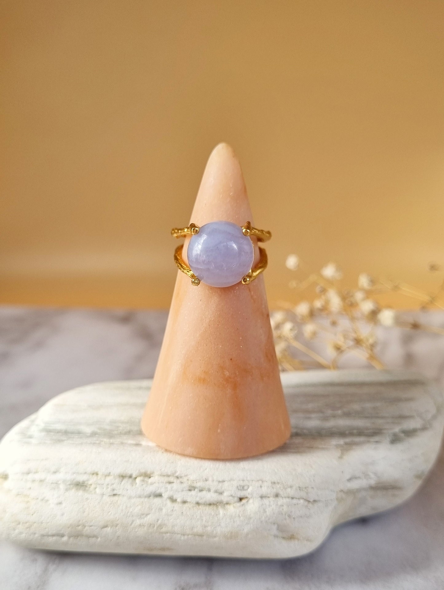 Natural blue lace agate gemstone ring, displayed on ring stand with white dried flowers in the background. Handmade in Australia.