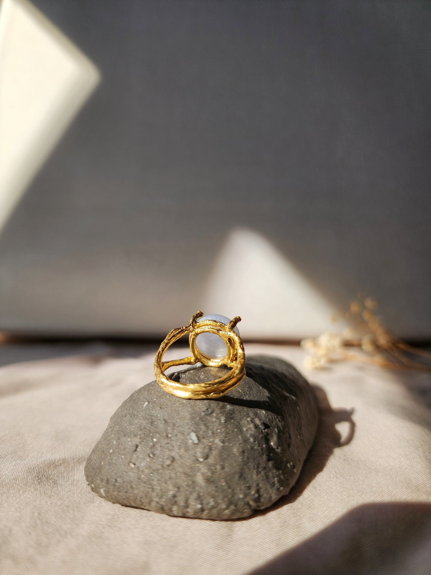 A blue lace agate ring, shown from the back to highlight the open gallery feature of the ring setting. The hand carved four prong double gallery basket setting features organic textures that captures the luminous natural blue crystal.