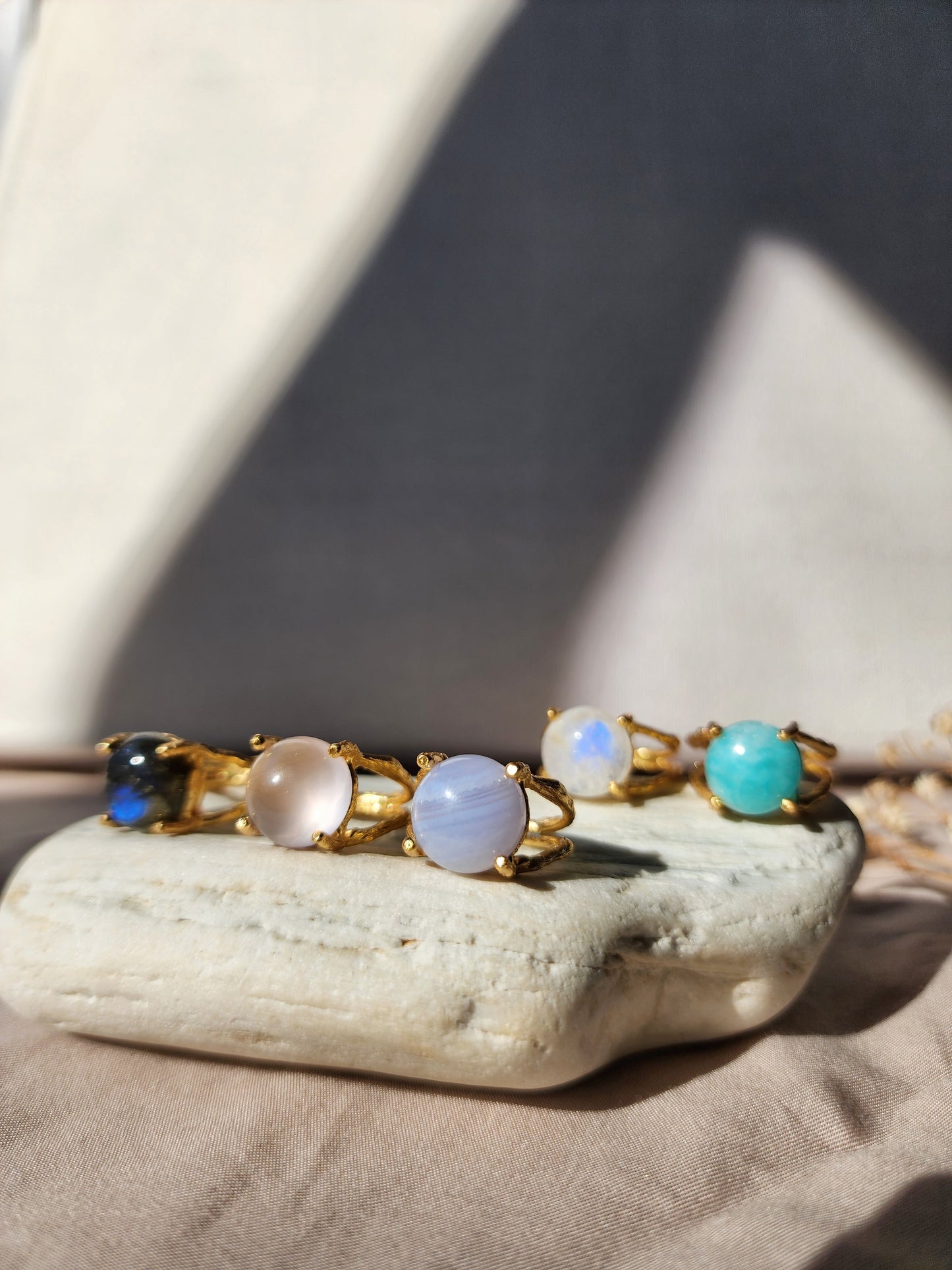 Set of natural gemstone rings, 12mm in size sitting on a white stone. Featuring the whole collection including blue lace agate, rose quartz, labradorite, amazonite and moonstone. Handmade in Australia and crafted using the old world lost wax technique. 