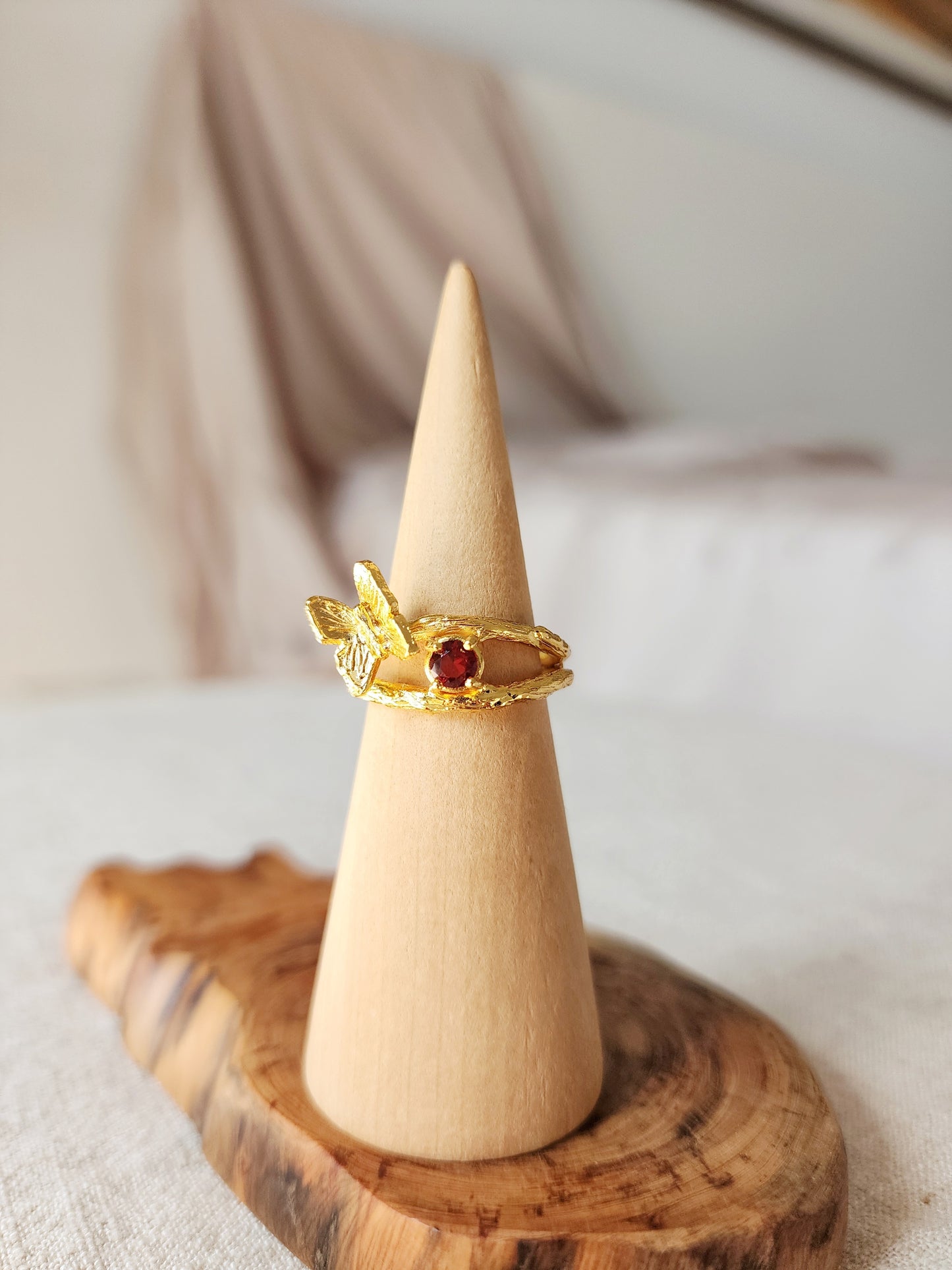 Natural ruby butterfly ring on a wood ring stand, highlighting the natural hand carved textures from the lost wax casting process. Crafted in 20k gold vermeil in Sydney with the gemstone ring set in an open back double gallery basket setting.