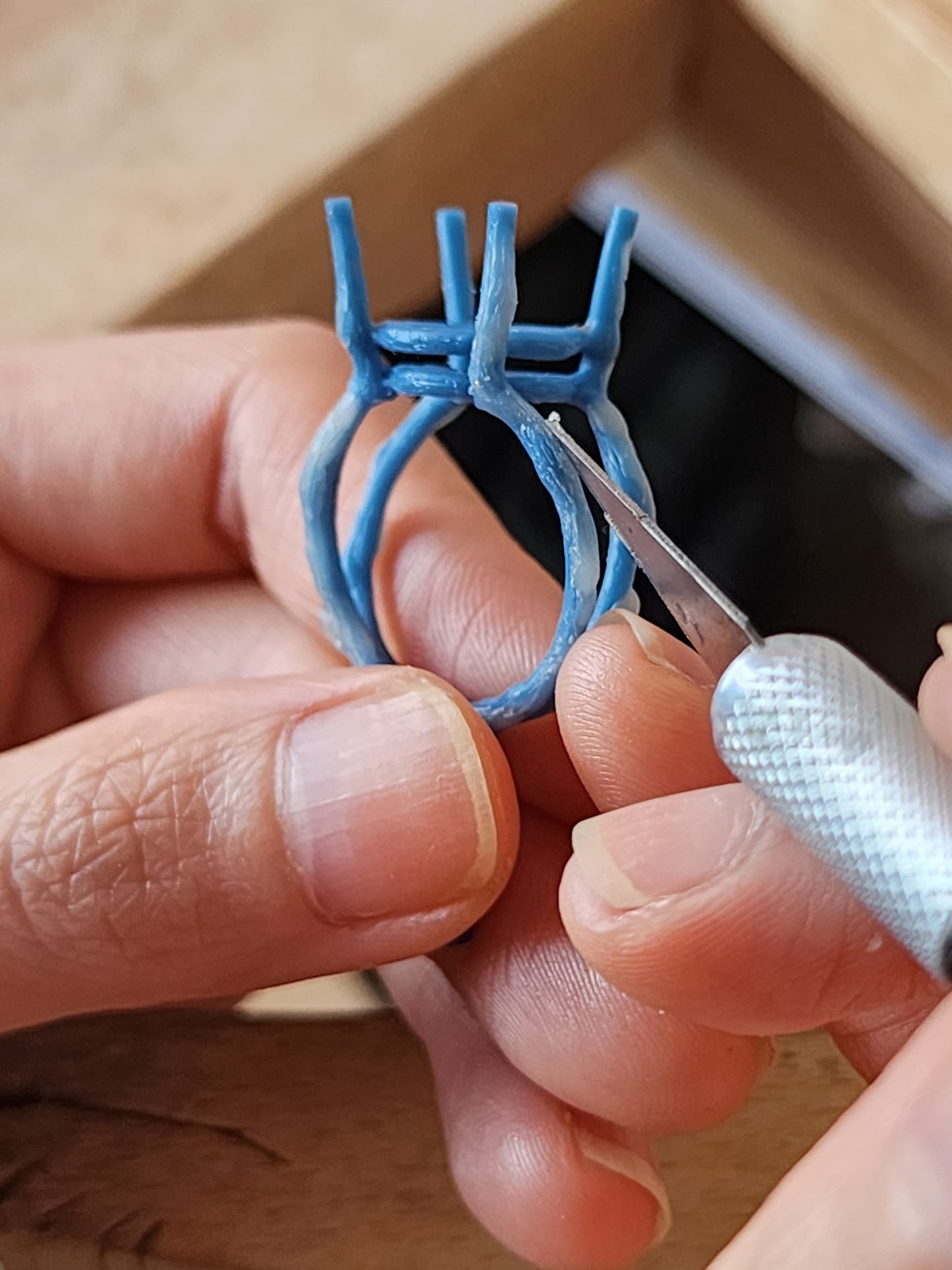 Close up of jewellers hands holding a ring that's been hand sculpted using traditional jewellers wax in a Sydney studio.