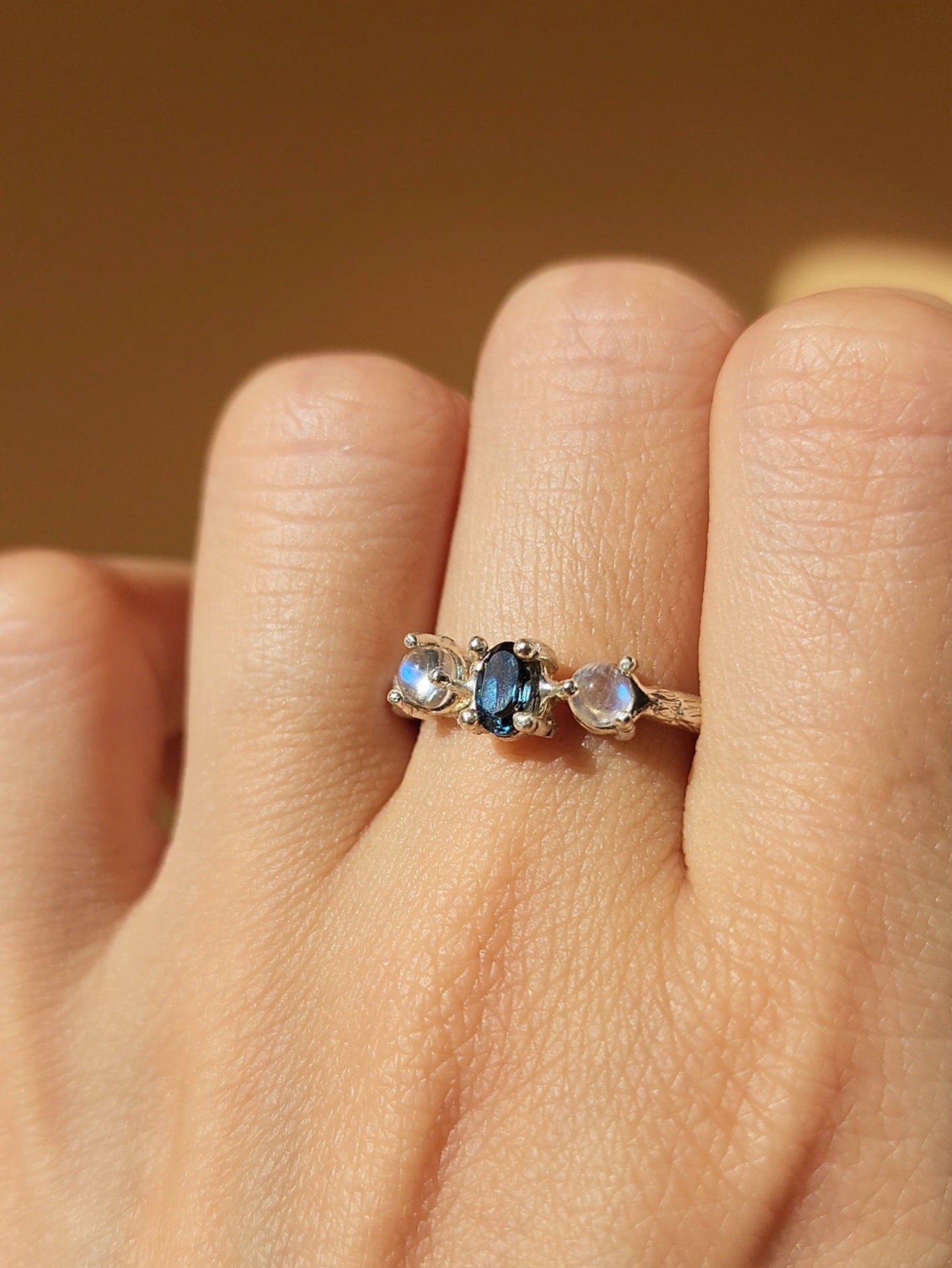 Moonstone and blue topaz ring, hand crafted in sterling silver shown up close to highlight the organic molten textures of the organic double gallery basket set gemstones. 
