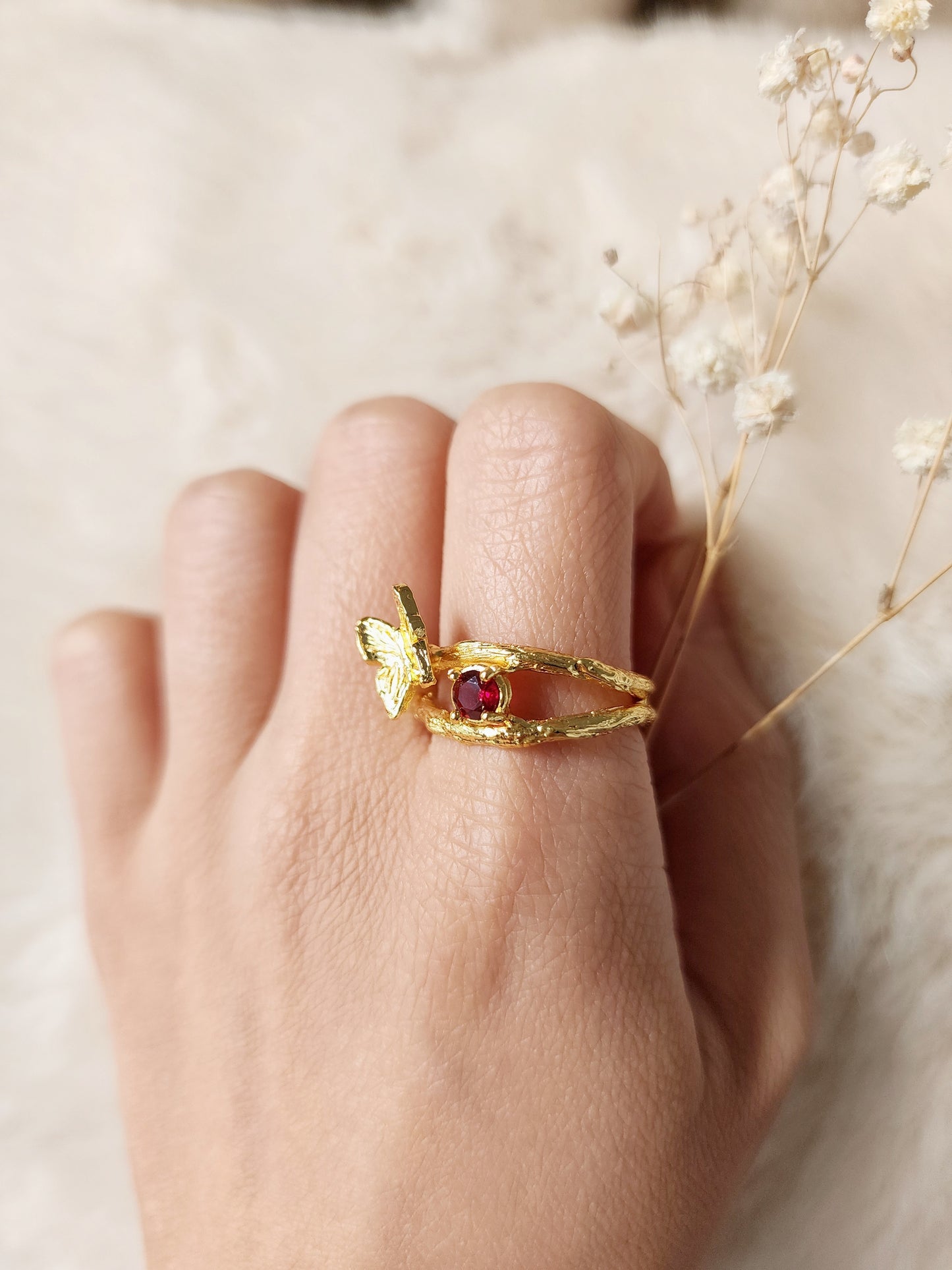 Ruby butterfly ring featuring natural precious gemstones, worn on woman's hand and highlighting up close details of the organic hand carved textures of the handmade ring. Crafted in 20k old vermeil in Sydney. 