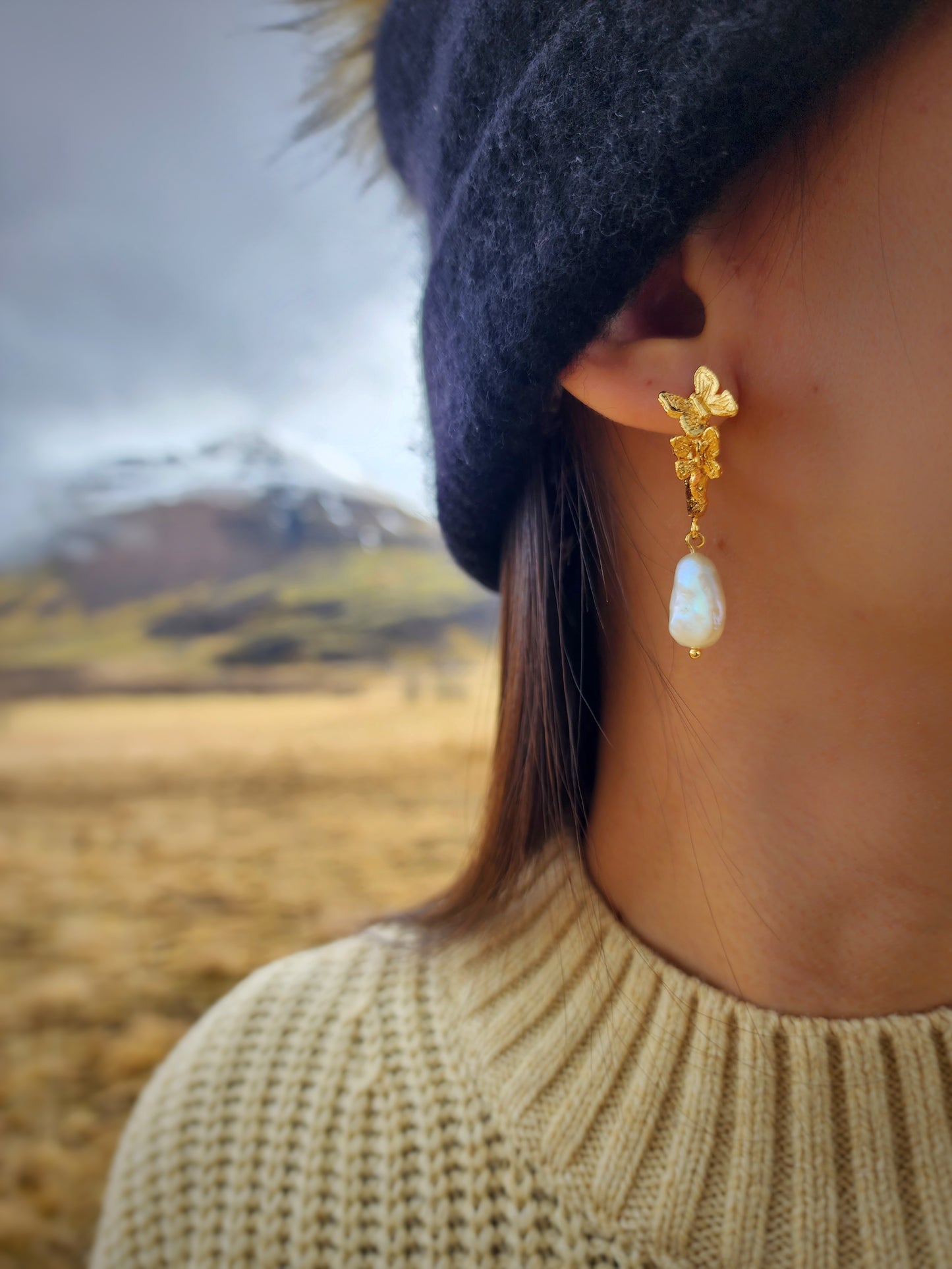 Pearl butterfly earrings in 18k gold vermeil with iridescent natural white freshwater pearls, hand sculpted in Sydney and styled in a natural mountain setting. 