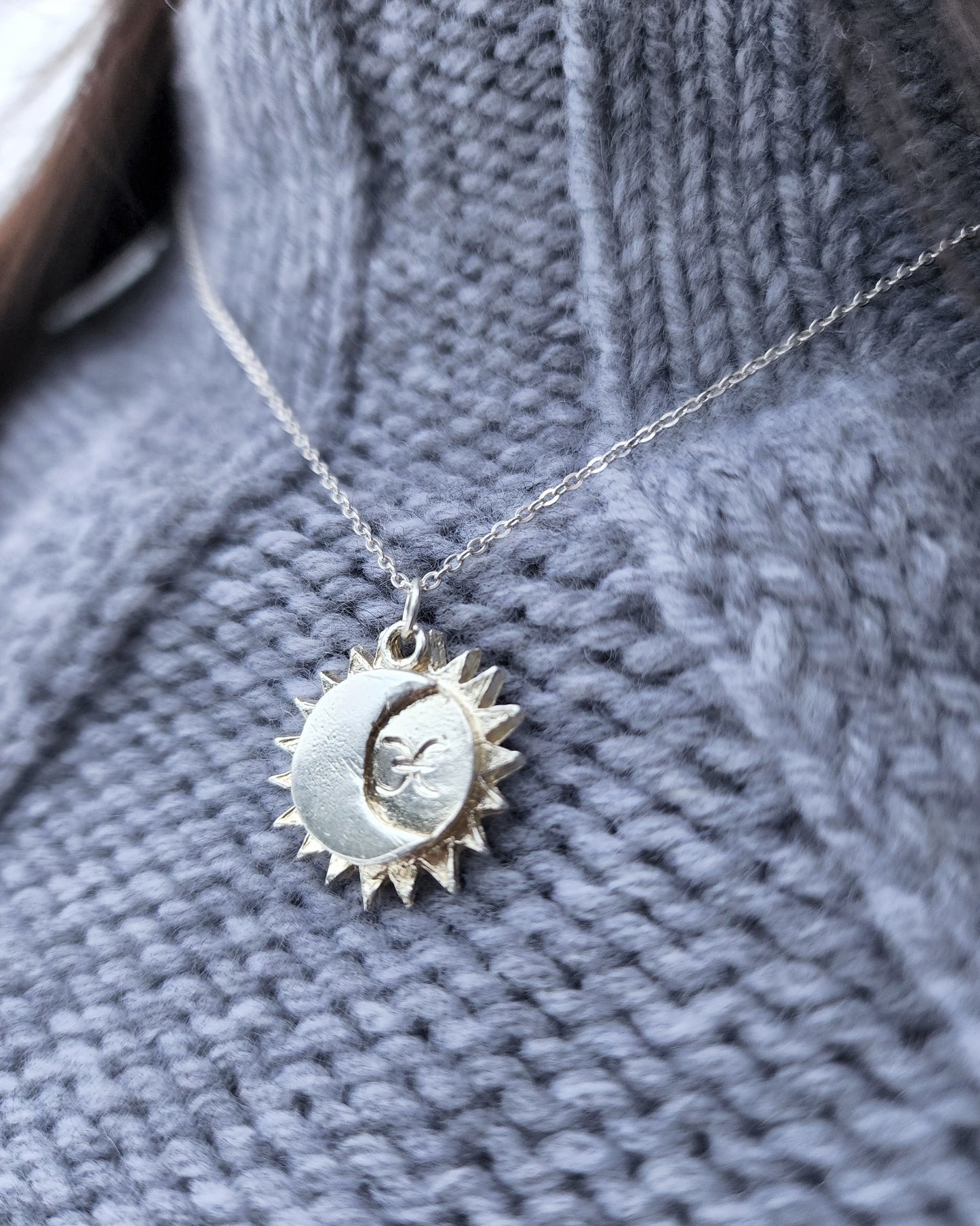 Sun and moon star sign necklace in sterling silver styled against a grey knit sweater.