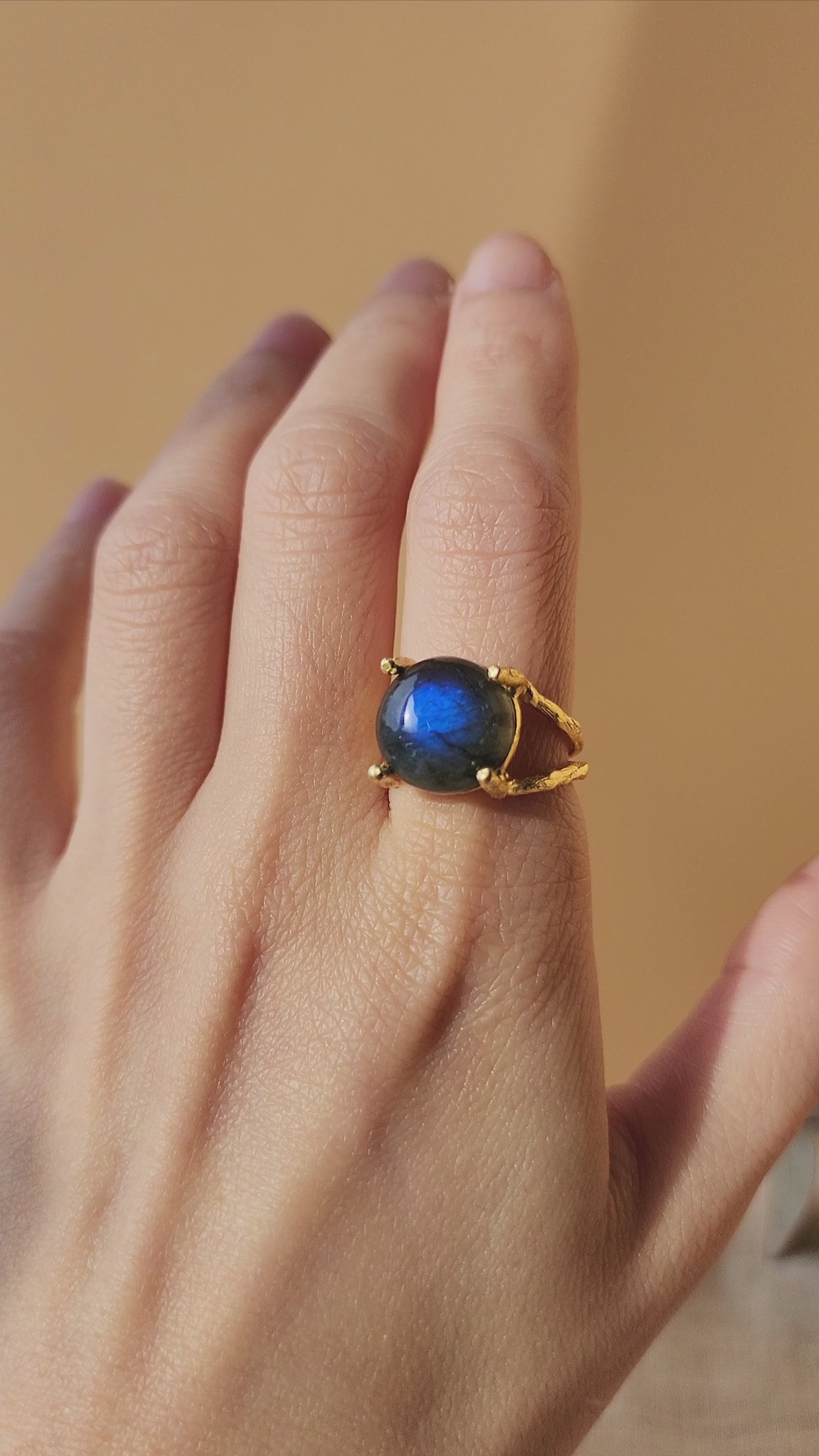 Labradorite natural gemstone ring, hand sculpted and made using the artisanal lost wax technique worn on models hand. The hand slowly moves to showcase multiple angles of the ring, highlighting the organic textures and the double gallery ring setting.