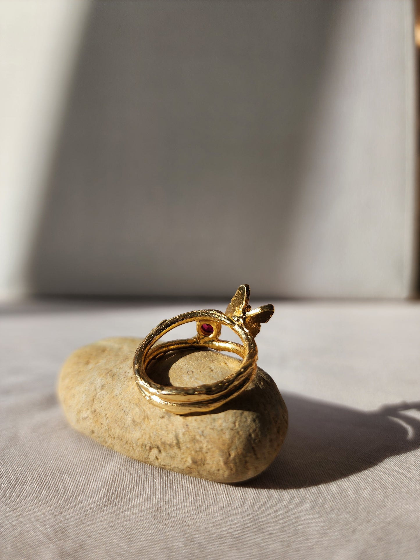 A hand made butterfly ring with a natural ruby, shown from behind to highlight the open back double gallery basket setting. Crafted in sydney in 20k gold vermeil. 